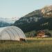 Mobile Rundbogenhalle in Schweizer Alpenlandschaft mit Chalet und schneebedeckten Bergen