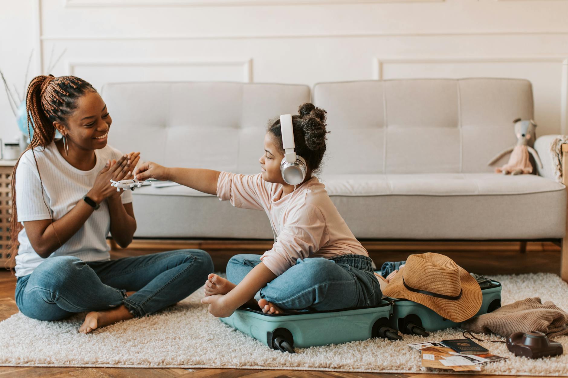 A joyful mother and daughter bond while packing a suitcase, preparing for a fun trip at home.